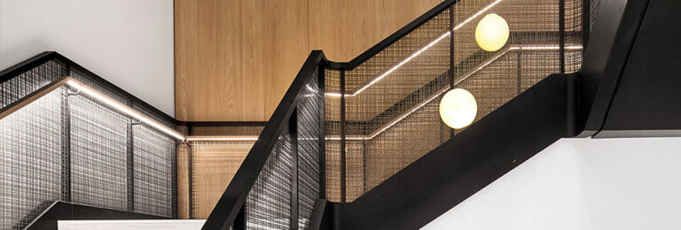 Banker SJD-21 Decorative Woven Wire Mesh in Plated Antique Brass used in Stairwell Infill Panels allowing natural light to flow through the space.