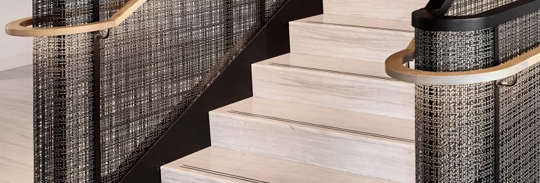 Banker SJD-21 Architectural  Woven Wire Mesh in Plated Antique Brass used in Stairwell Infill Panels allowing natural light to flow through the space.