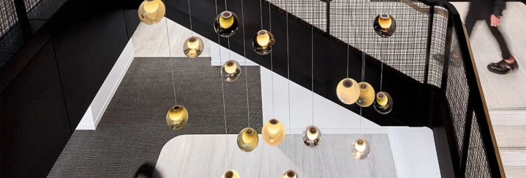 Banker SJD-21 Decorative Woven Wire Mesh in Plated Antique Brass used in Stairwell Infill Panels allowing natural light to flow through the space.